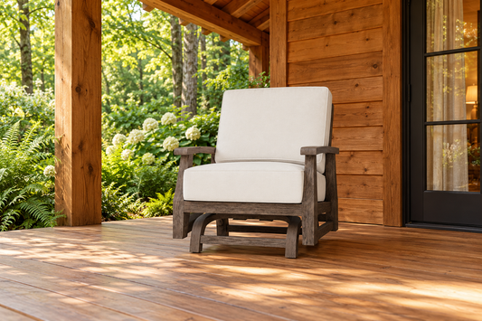 Lloyd Flanders Frontier Spring Rocker, sold individually, in an AI-styled cedar cabin porch setting with a wood deck and leafy garden.