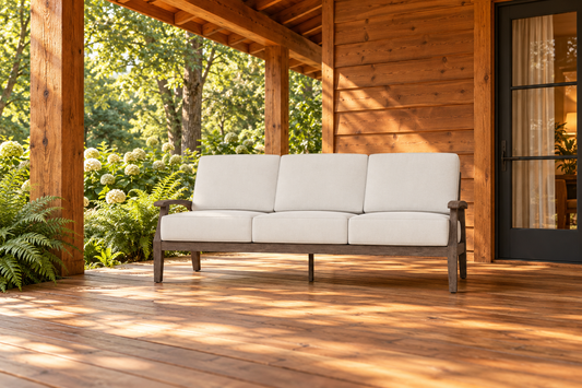 Lloyd Flanders Frontier Sofa, sold individually, in an AI-styled cedar cabin porch setting with a wood deck and leafy garden.