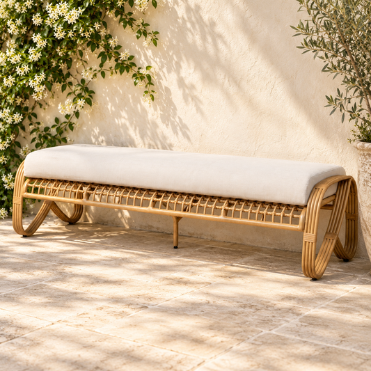 Lloyd Flanders Riviera Garden Bench positioned along an ivory patio wall with jasmine and olive greenery